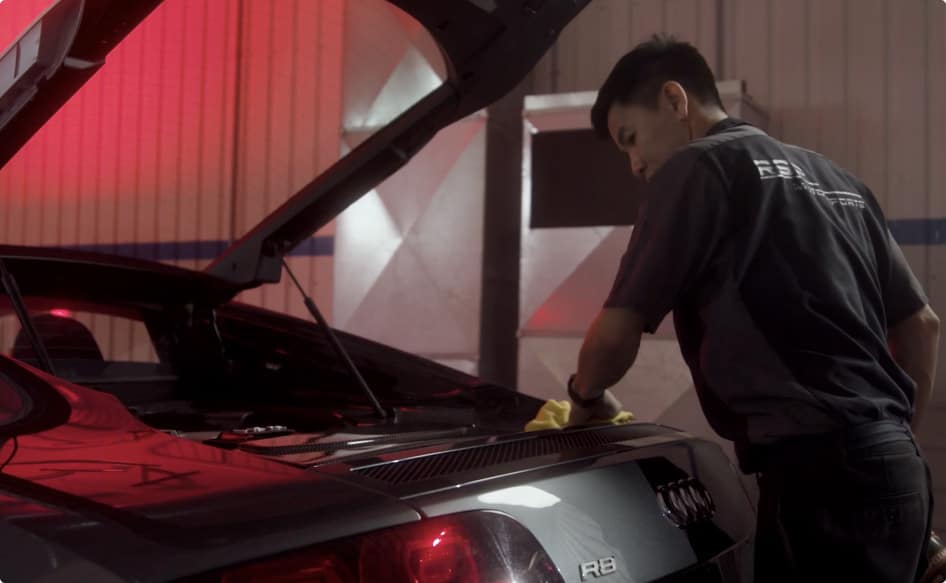 Detailing technician hand cleaning the trunk of an Audi