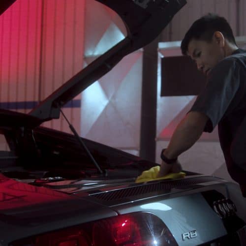 Detailing technician hand cleaning the trunk of an Audi