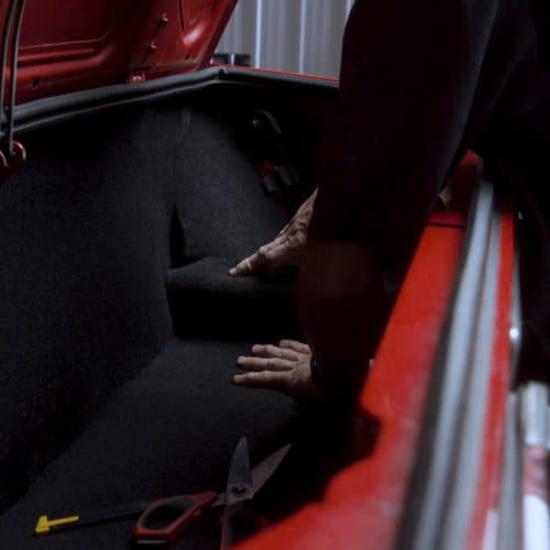 Detailing technician cleaning the upholstery in the trunk of an Audi
